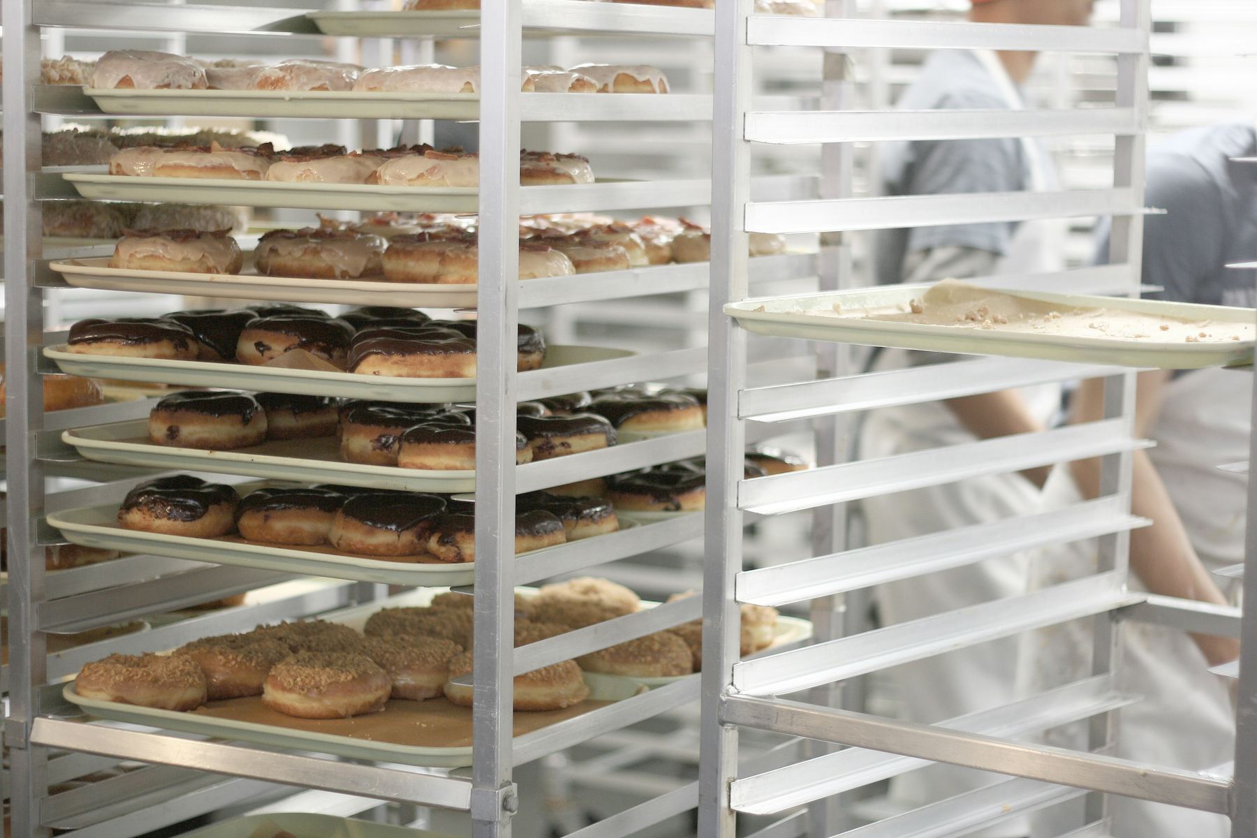 Trays of freshly glazed bakery products on racks in a commercial bakery
